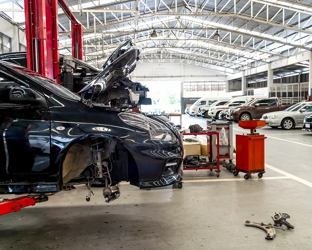 Garage automobile avec voiture noire sur cric, capot ouvert, en cours de réparation Les Essarts-le-Roi dans les Yvelines 78