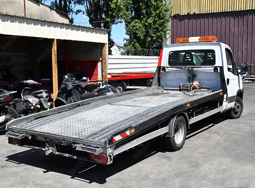 Dépanneuse blanche avec plateau vide, stationnée près d'un garage et de motos Les Essarts-le-Roi dans les Yvelines 78