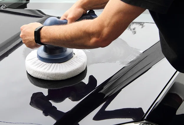 Un homme polissant une voiture noire brillante avec un polisseur orbital Les Essarts-le-Roi dans les Yvelines 78